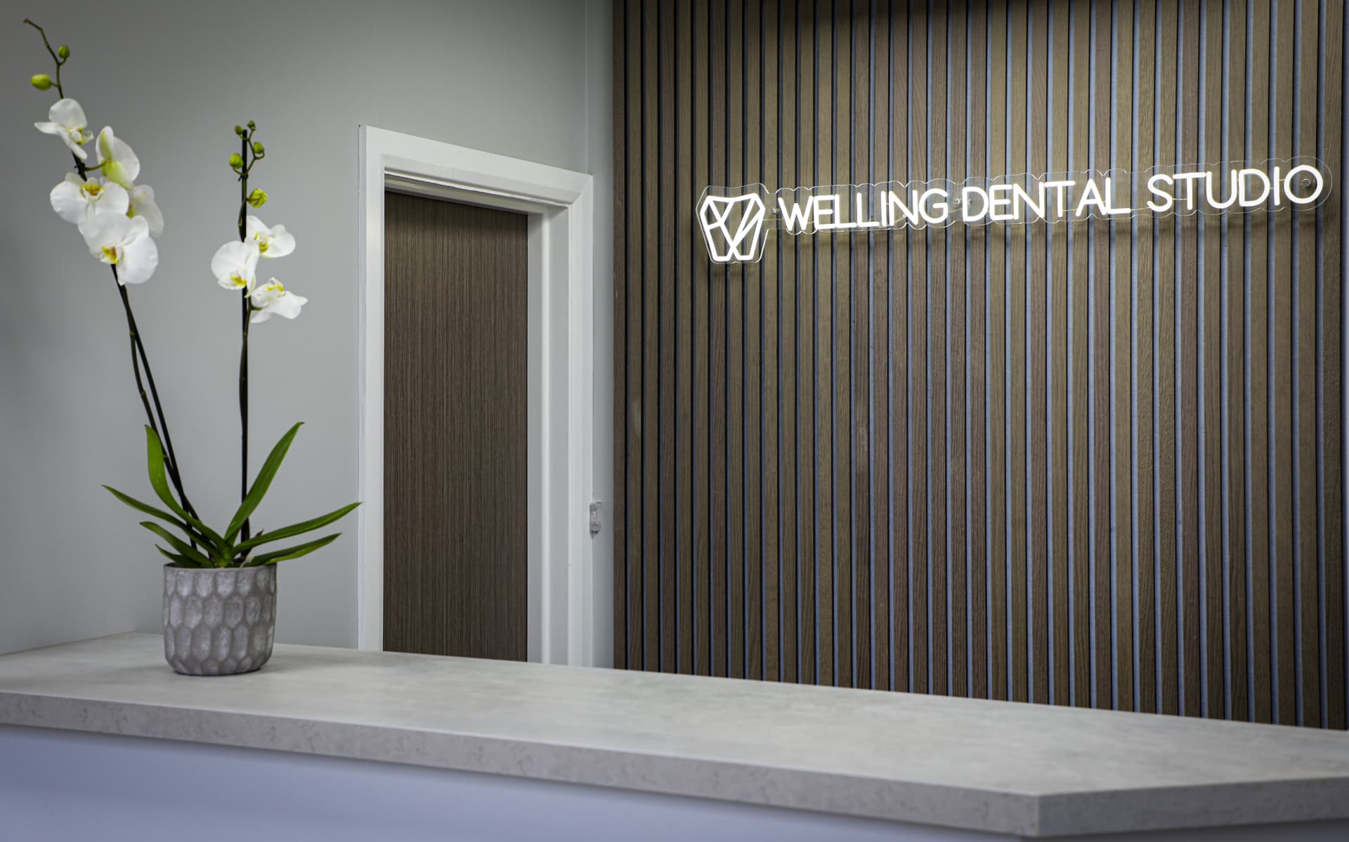 Reception desk and neon Welling Dental Studio sign
